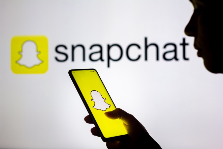 BRAZIL - 2022/03/28: In this photo illustration, a woman's silhouette holds a smartphone with the Snapchat logo displayed on the screen and in the background. (Photo Illustration by Rafael Henrique/SOPA Images/LightRocket via Getty Images)
