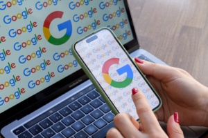 ANKARA, TURKIYE - SEPTEMBER 03: A woman looks at a mobile phone displaying the logo of Google in front of a laptop screen displaying the logo of Google in Ankara, Turkiye on September 03, 2024. (Photo by Dilara Irem Sancar/Anadolu via Getty Images)