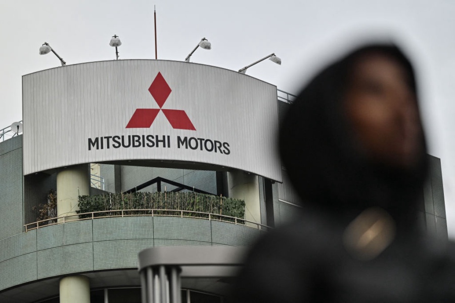 A pedestrian walks past a branch office of Japanese automaker Mitsubishi Motors along a street in Tokyo on February 3, 2025. Mitsubishi Motors were expected to announce their third quarter earnings on February 3. (Photo by Richard A. Brooks / AFP) (Photo by RICHARD A. BROOKS/AFP via Getty Images)