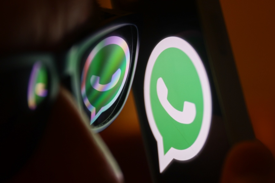 WhatsApp logo reflected on sunglasses and displayed on a phone screen. (Photo by Jakub Porzycki/NurPhoto via Getty Images)