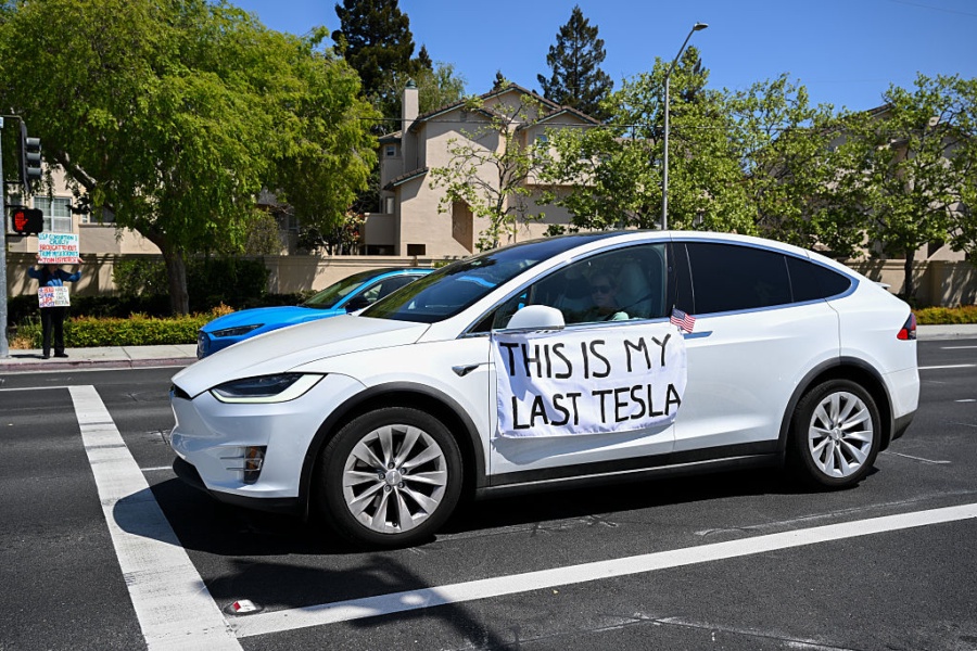 PALO ALTO, CALIFORNIA - APRIL 12: A Tesla owner hangs a written note on her car drives by as anti-Tesla protesters are gathered outside of a Tesla dealership on El Camino Real to protest President Trump and Elon Musk in Palo Alto, California, United States on April 12, 2025. (Photo by Tayfun Coskun/Anadolu via Getty Images)