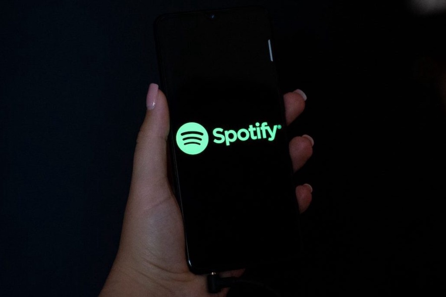 Hand holding a mobile phone with the logo of Spotify on its screen.