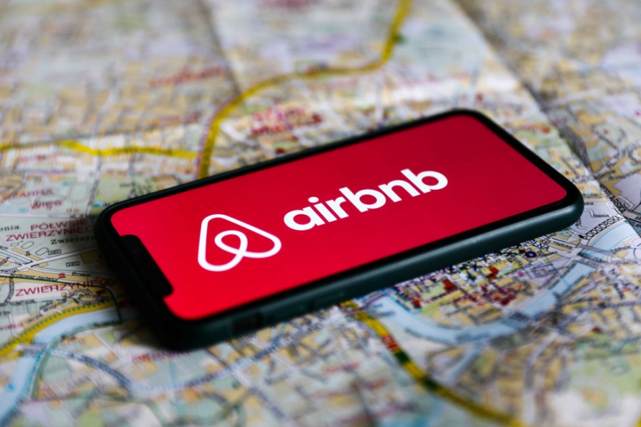 Airbnb logo displayed on a phone screen laying on a map of Krakow
