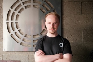 Durin founder Ted Feldmann stands before metal art.