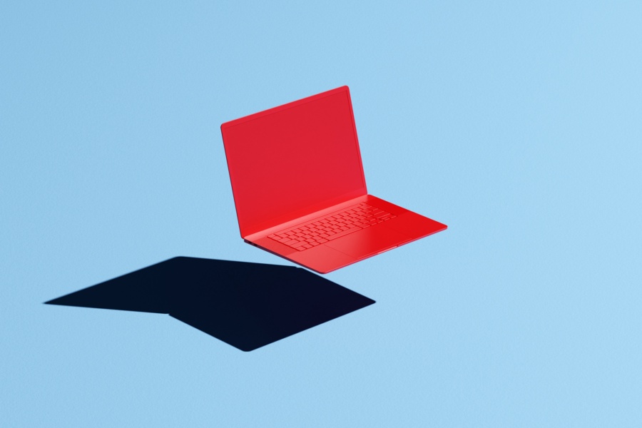 Conceptual image of a red laptop floating mid-air on a blue background with a hard shadow