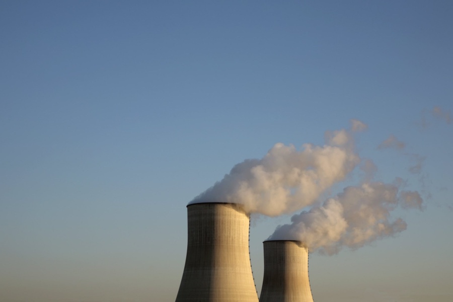 Cooling towers for a nuclear reactor stand against a blue sky.